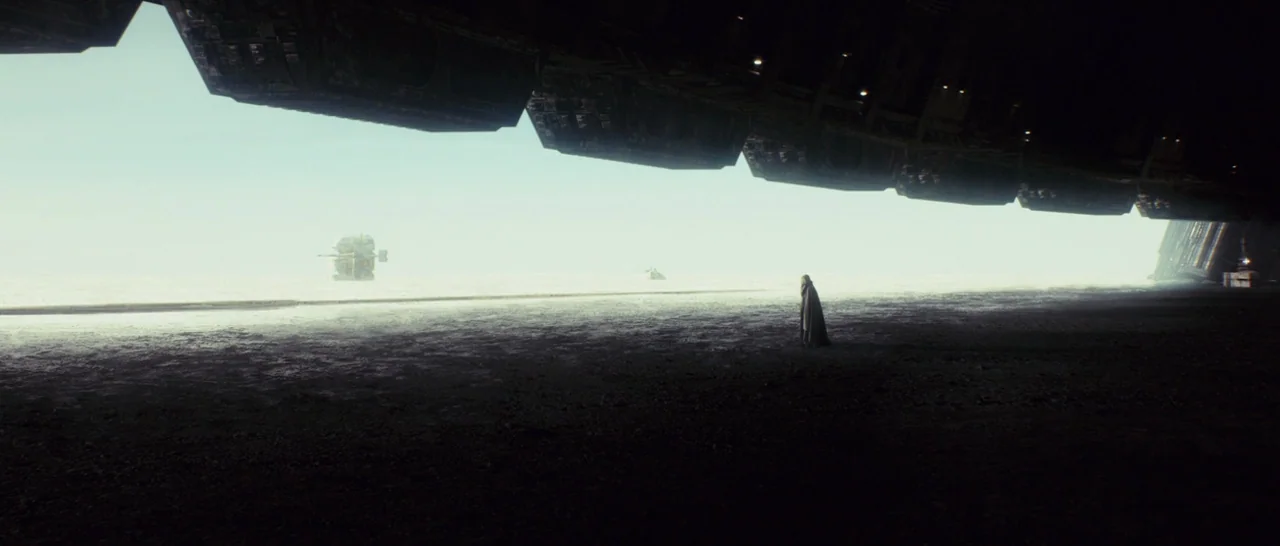 Star Wars: The Last Jedi (2017) movie still: wide — A dark, expansive hangar interior overlooks a bright, featureless landscape under a pale sky. A…