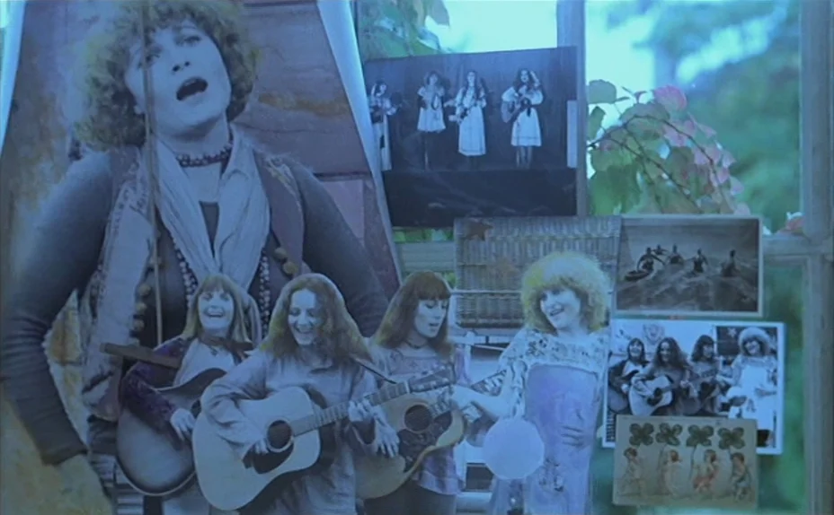 L’une Chante, l’Autre Pas (1977) movie still: closeup — A collection of vintage photographic prints is taped and layered onto a glass window pane.…