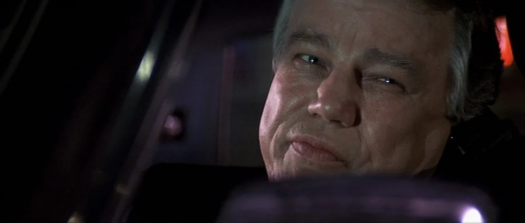 Cape Fear (1991) movie still: closeup — The interior of a car at night with a man behind the wheel. The man looks toward the side window while…