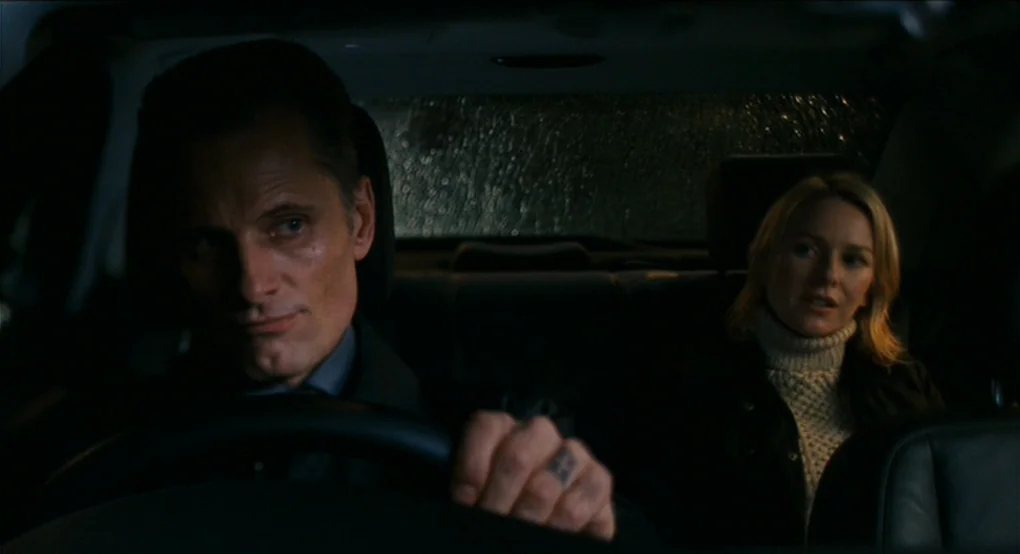 Eastern Promises (2007) movie still: medium — The interior of a dark car at night shows a man driving and a woman. Rain streaks cover the rear…