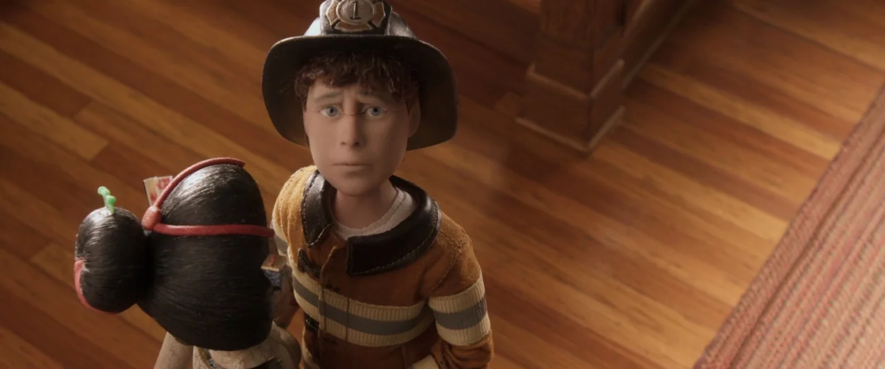 Anomalisa (2015) movie still: medium — A wooden floor room serves as the setting for two stop-motion character puppets. The boy puppet wearing a…