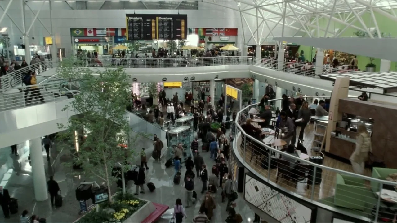 The Terminal (2004) movie still: wide — A busy multi-level airport terminal features glass railings, white structural beams, and large departures…