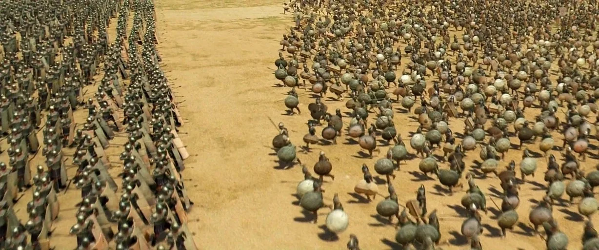 Troy (2004) movie still: wide — A vast, flat, arid desert landscape provides a venue for two opposing armies. Thousands of soldiers in bronze armor…