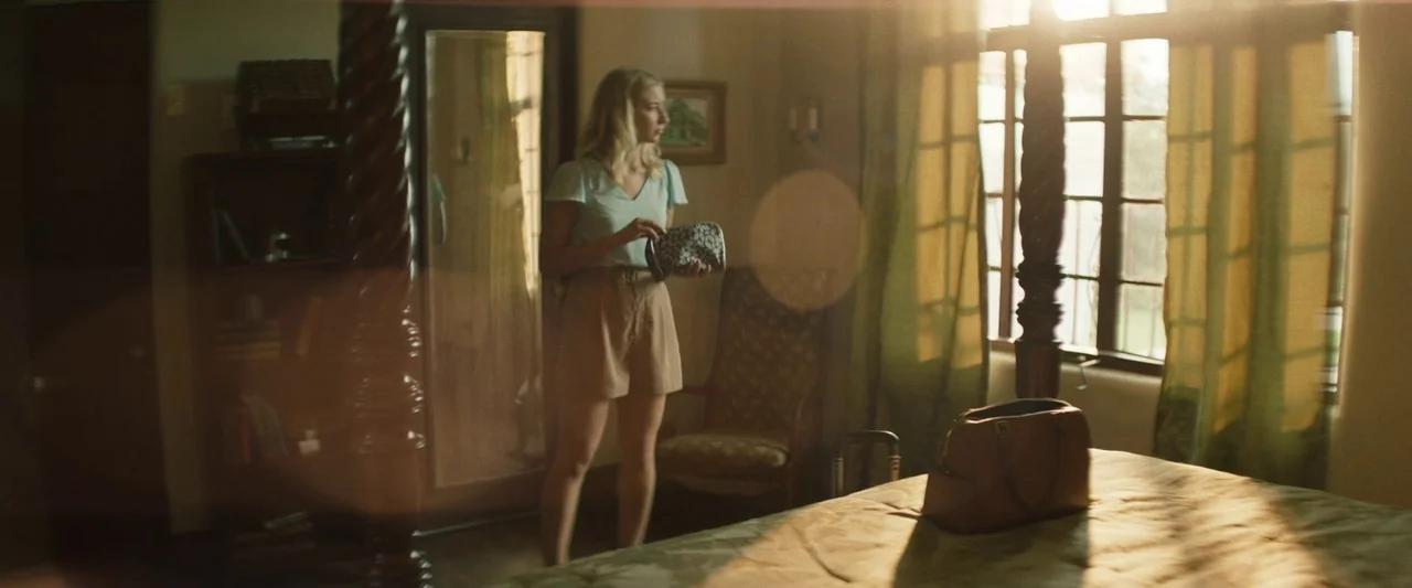 The Mad Hatter (2021) movie still: fullbody — A sunlit room features dark wood furniture and curtains illuminated by warm afternoon light. A young…
