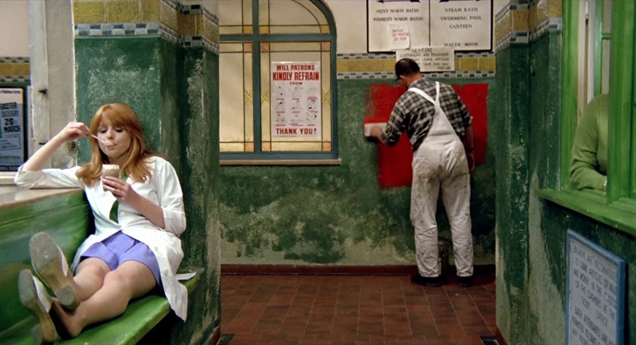 Deep End (1970) movie still: fullbody — A public bathhouse features green tile walls, a terracotta tiled floor, and vintage signage. A woman in a…