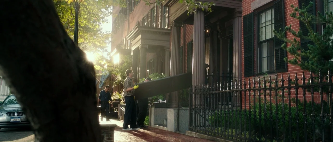 The Purge: Election Year (2016) movie still: wide — A sidewalk in front of residential brick row houses with black iron fencing. Several men work…