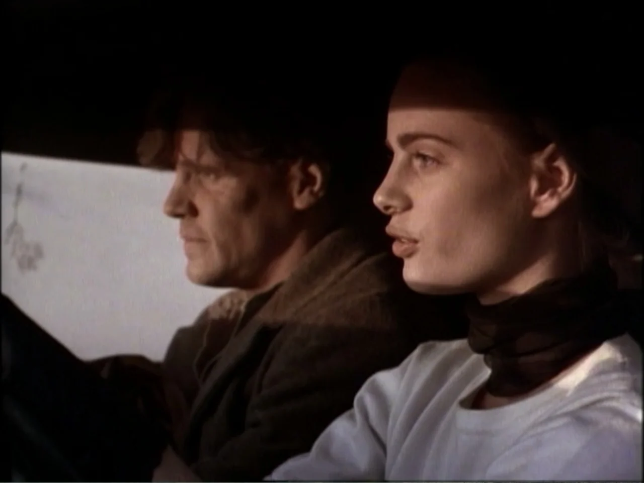 In Pursuit of Honor (1995) movie still: medium — The interior of a moving car at night is dark and dimly illuminated. A young woman and an older man…