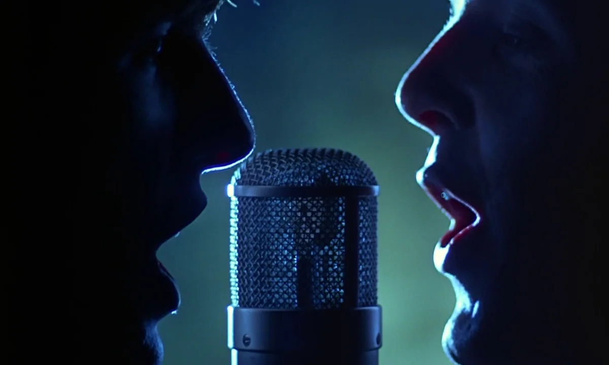 Help! (1965) movie still: closeup — Two individuals stand in a dark, dimly lit professional recording studio. They stand facing each other, singing…