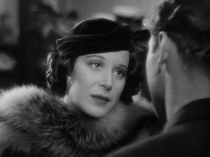 A Night at the Opera (1935) movie still: closeup — A dimly lit interior setting features a woman wearing a velvet hat and fur. She gazes past the…