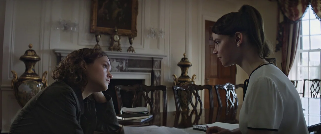 Thoroughbreds (2017) movie still: medium — A formal dining room contains dark wood furniture, ornate urns, and a mantle clock. Two women sit at the…