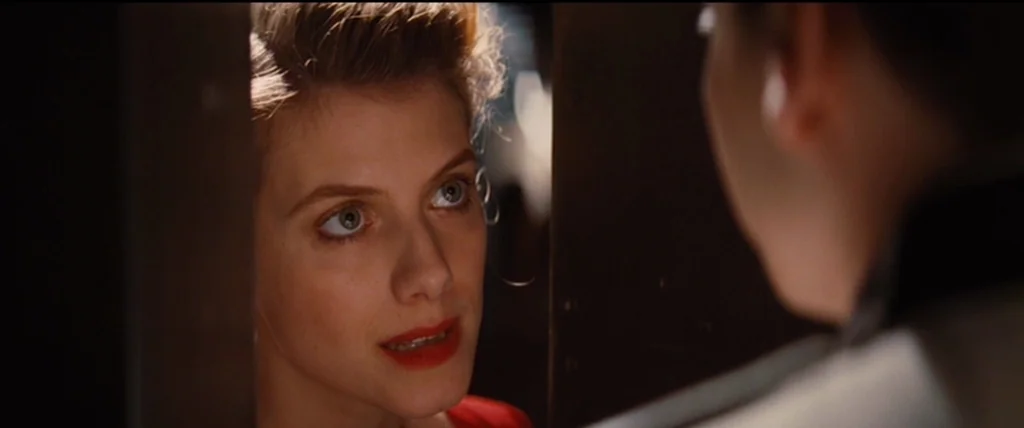 Inglourious Basterds (2009) movie still: closeup — A woman looks through a vertical gap in a dark wooden door frame. She gazes at an out-of-focus…