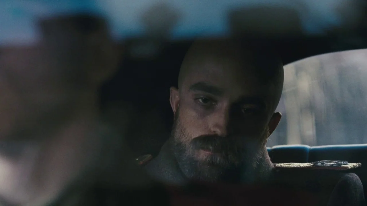 Childhood of a Leader (2015) movie still: closeup — The interior of a moving vintage vehicle with dark upholstery and military uniform detailing. A…