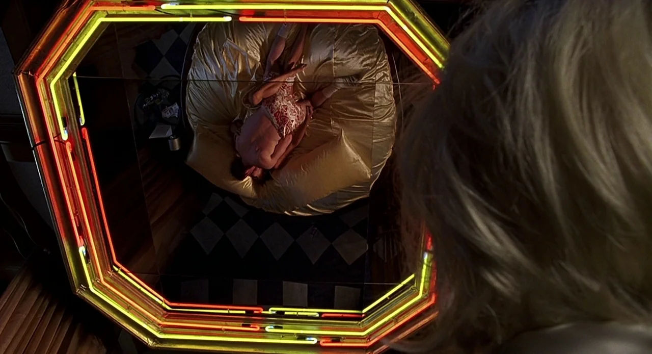 Bride of Chucky (1998) movie still: medium — A room features a large octagonal mirror with neon tubing reflecting a circular bed. A person stands in…
