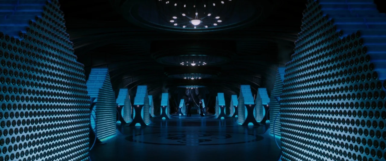 Jupiter Ascending (2015) movie still: wide — A vast, dark symmetrical chamber is filled with glowing blue tiered storage structures. Circular…