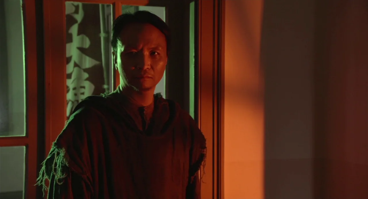 Hanagatami movie still: medium — A dimly lit indoor space features a glass door with visible calligraphic signage. A man stands in the foreground,…