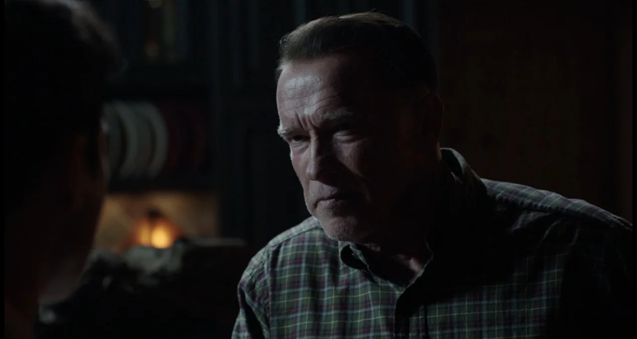 Sabotage (2014) movie still: medium — A dimly lit interior room at night contains blurred shelving in the background. An older man in a plaid shirt…