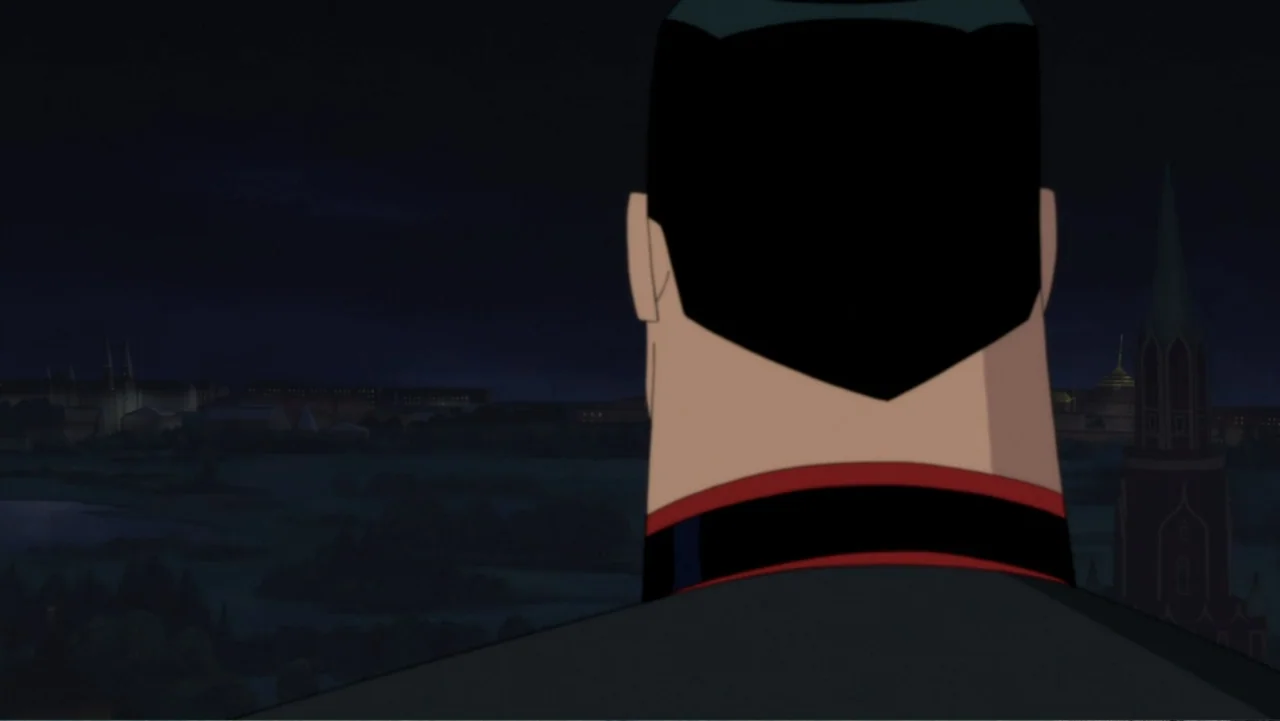 Superman: Red Son (2020) movie still: medium — A man stands on a dark balcony looking over a night cityscape with spires. The subject is seen from…