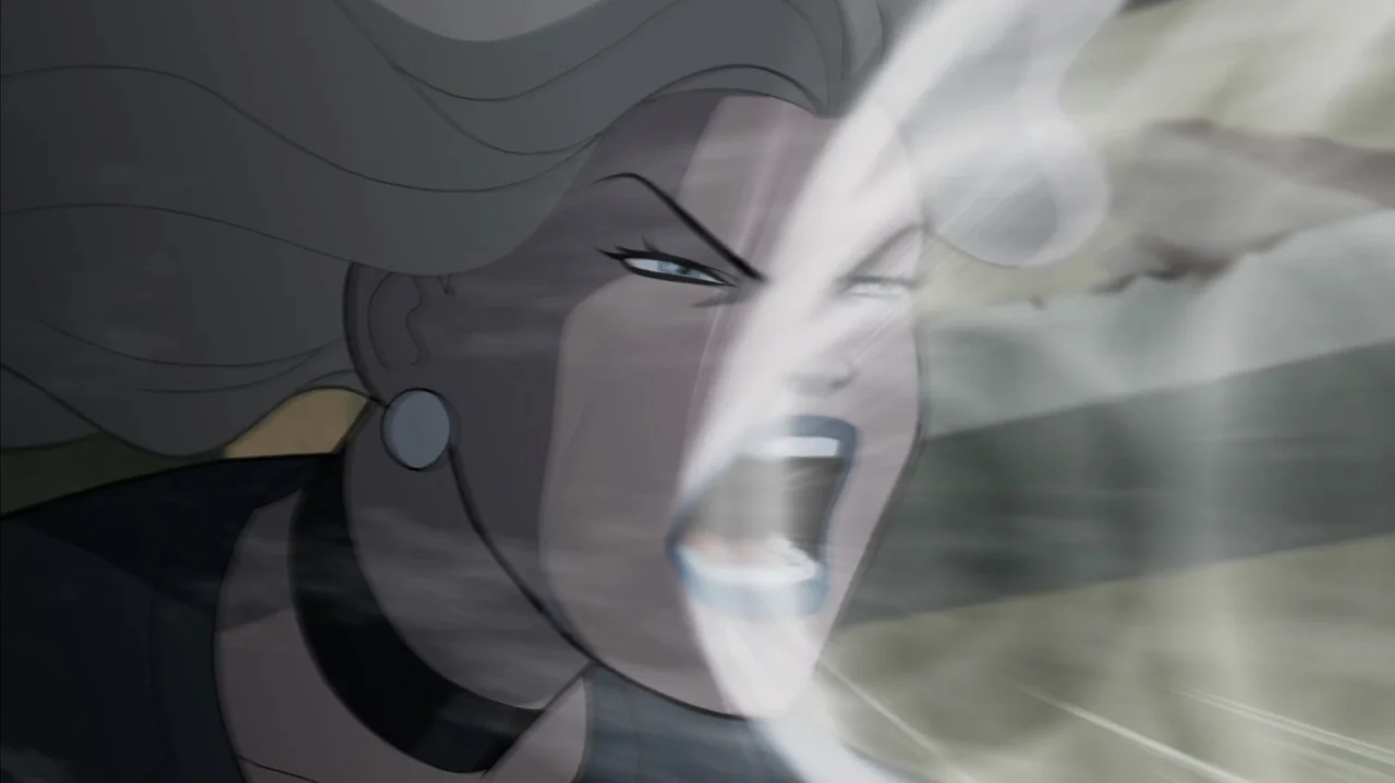 Justice Society: World War II (2021) movie still: closeup — A woman with flowing hair stands in an open space filled with blowing dust. The subject…