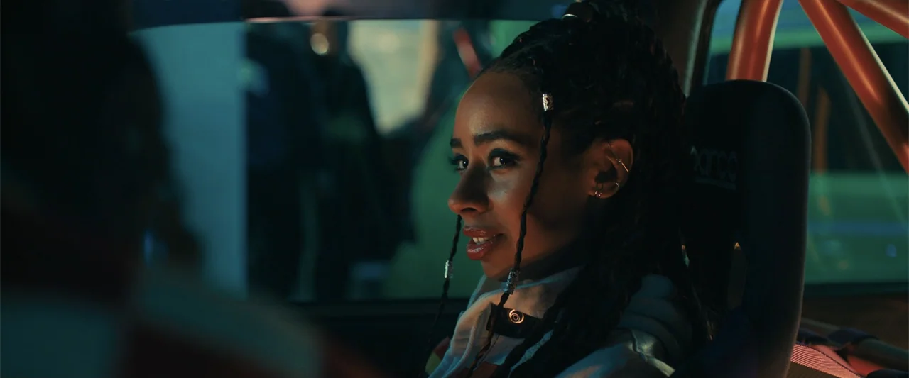My Fault: London (2025) movie still: medium — Inside a vehicle at night, the dashboard and seats are visible in dim light. A young woman with…