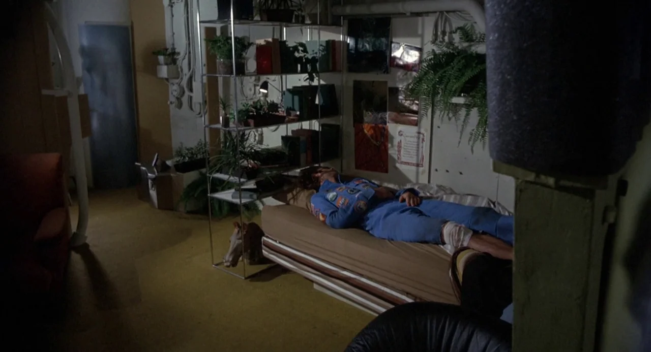 Silent Running (1972) movie still: wide — A utilitarian room features a single bed against a wall decorated with photographs. A man wearing a blue…