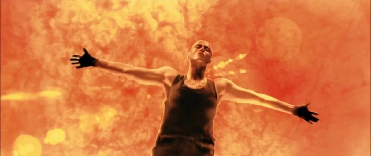 Alien 3 (1992) movie still: medium — A bald man stands with arms wide open against a glowing orange field. The bright light washes out details,…