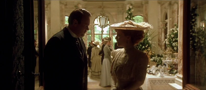 The House of Mirth (2000) movie still: medium — A lavish conservatory features marble pillars and floor-to-ceiling windows overlooking a green…