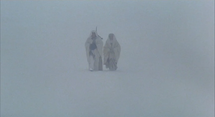 Quintet (1979) movie still: wide — A vast, featureless snowy landscape is obscured by heavy white fog and blizzard conditions. Two figures wearing…
