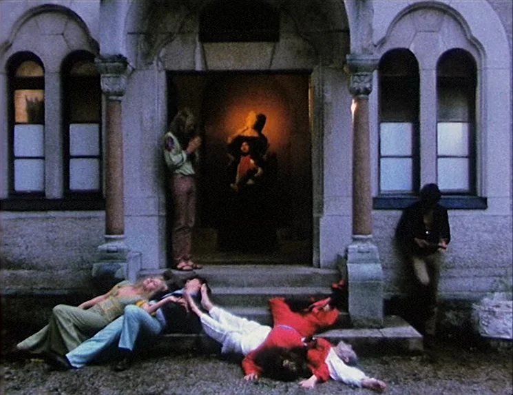 The Niklashausen Journey (1970) movie still: fullbody — A stone building with arched doorways and windows serves as the setting for the group.…