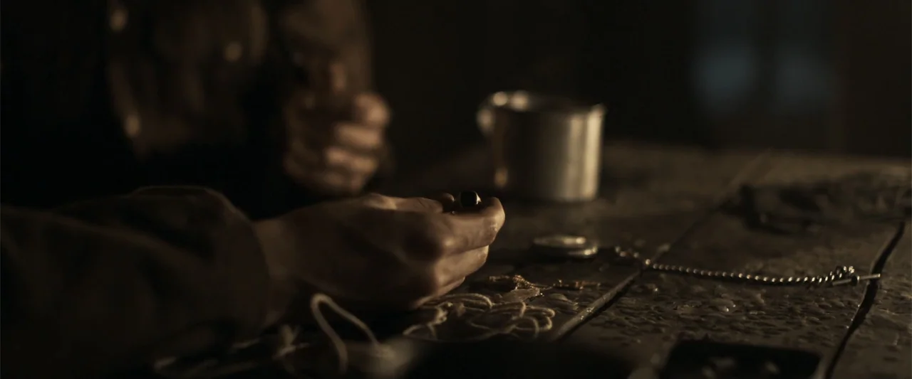 Gone Missing -  Old John's Final Journey (2014) movie still: closeup — A dark interior space contains a rough-hewn wooden table with assorted metal…