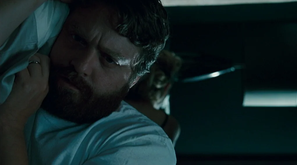 Visioneers (2008) movie still: closeup — A dark bedroom interior with minimal visible details beyond the subject in focus. A man with a beard lies…