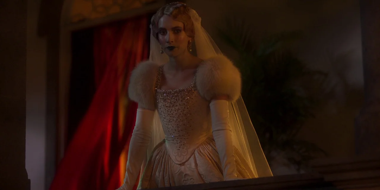Paradise Hills (2019) movie still: medium — A dimly lit staircase landing features dark stone walls and deep red curtains. A woman wearing an ornate…