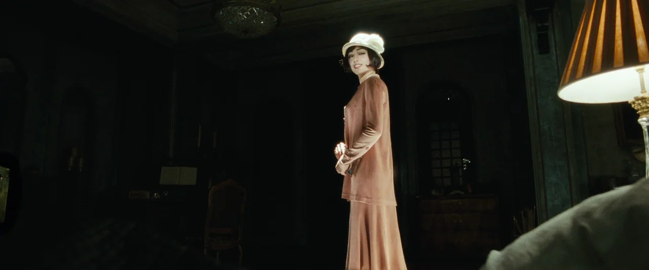 Chicken With Plums (2011) movie still: fullbody — A dimly lit room features vintage furniture and a low-hanging chandelier in the background. A…