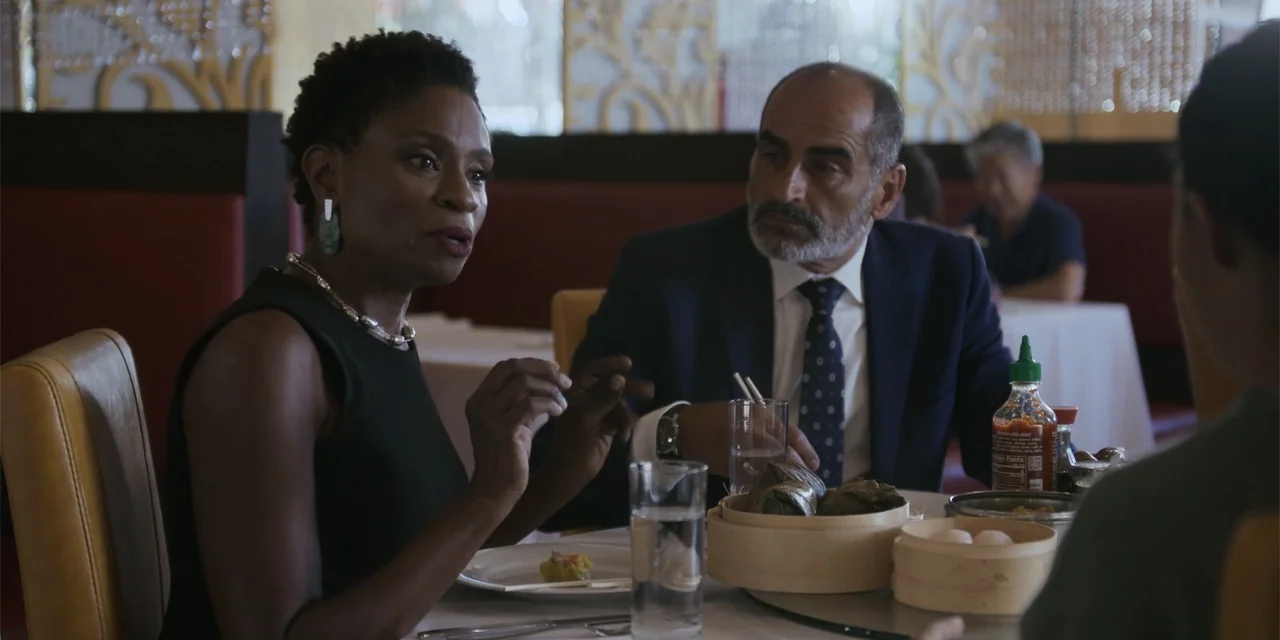 Sitting in Bars with Cake (2023) movie still: medium — A restaurant booth with red seating and white tablecloths contains dim sum service ware. A…