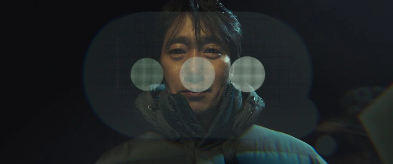 Decision To Leave (2022) movie still: closeup — A dark environment surrounds a man staring into a glowing digital interface. Three distinct bright…