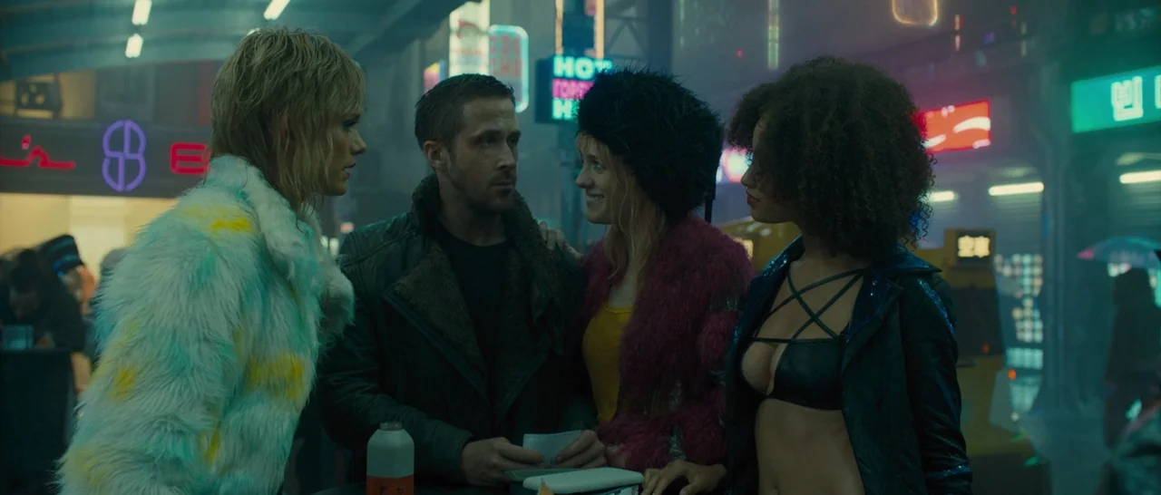 Blade Runner 2049 (2017) movie still: medium — A neon-lit urban environment at night filled with glowing signs and industrial structures. Four…