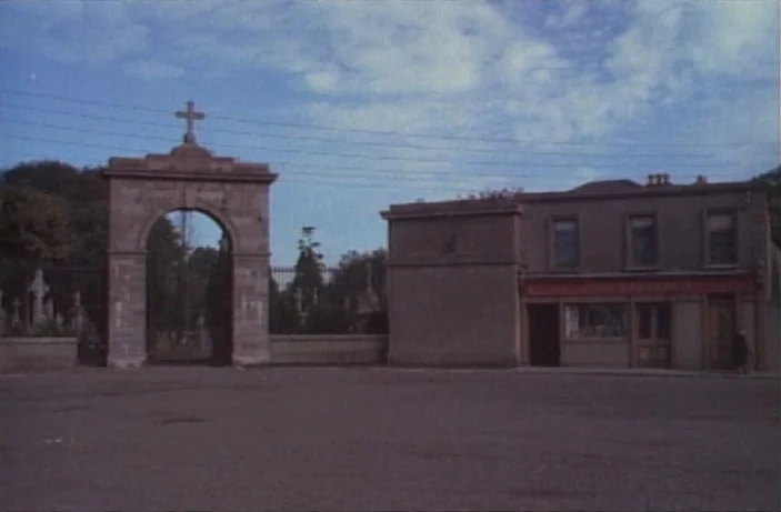 Quackser Fortune Has a Cousin in the Bronx (1970) movie still: establishing — A stone archway with a cross on top stands next to a two-story…