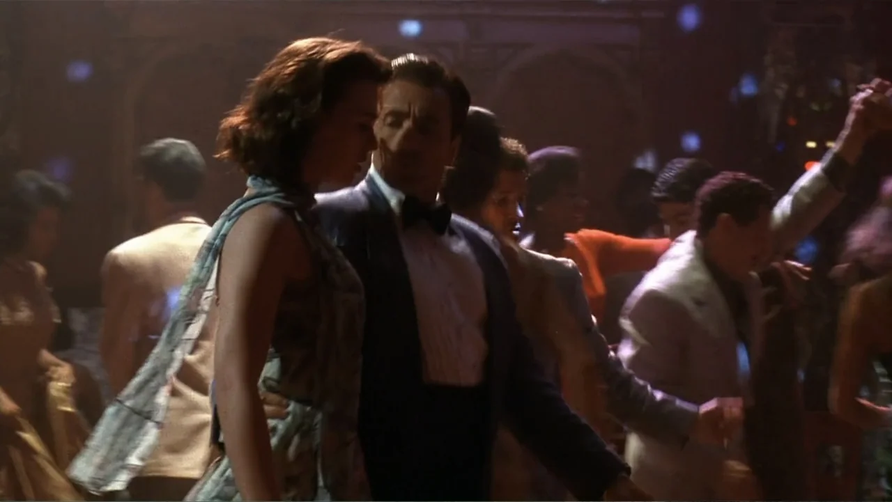 The Mambo Kings (1992) movie still: medium — A crowded dance floor features couples moving in a dim, period-appropriate social hall. A man in a…