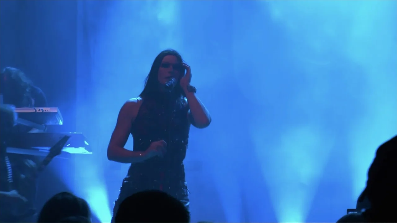 Soaring Highs and Brutal Lows: The Voices of Women in Metal (2015) movie still: medium — A musician performs on a dark concert stage bathed in…