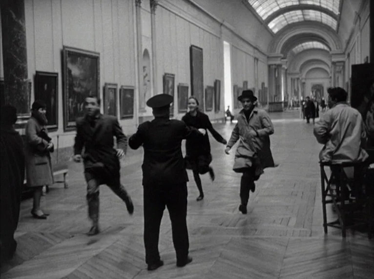Band of Outsiders (Bande à part) (1964) movie still: fullbody — A long, vaulted art gallery hall features paintings mounted along high white walls.…