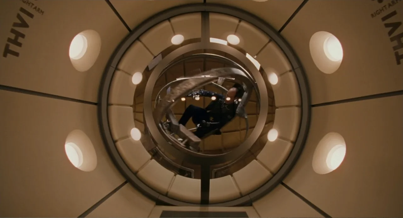 Meet Dave (2008) movie still: medium — A circular training centrifuge features padded white walls and glowing circular light fixtures. A man sits…
