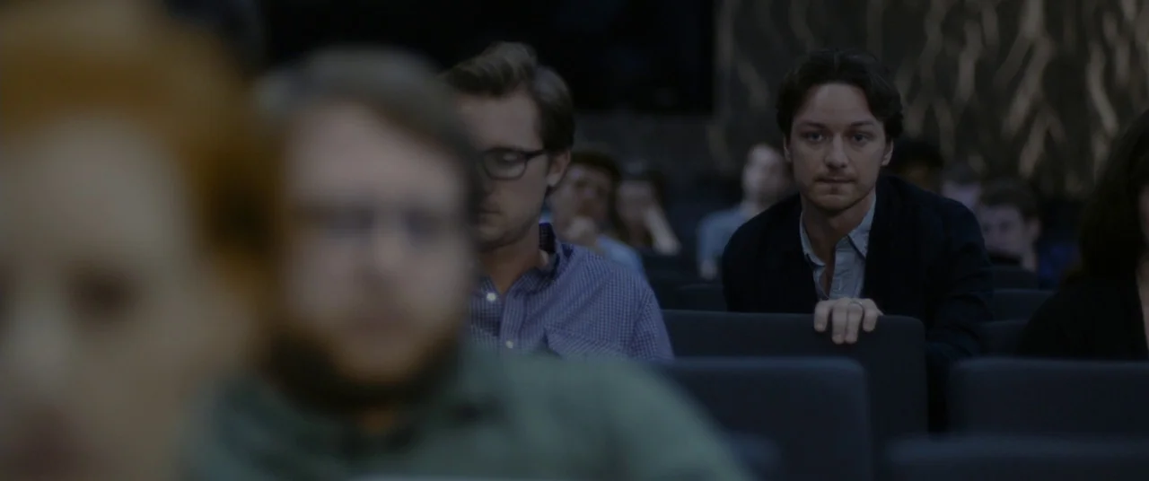 The Disappearance of Eleanor Rigby: Him (2014) movie still: medium — A dark, modern lecture hall contains rows of dark grey seats for attendees. A…
