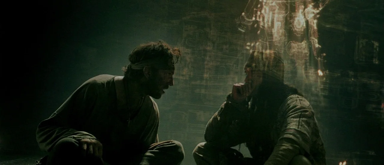 Renegade (2004) movie still: medium — A dark subterranean space features stone walls carved with intricate, glowing geometric patterns. Two men…