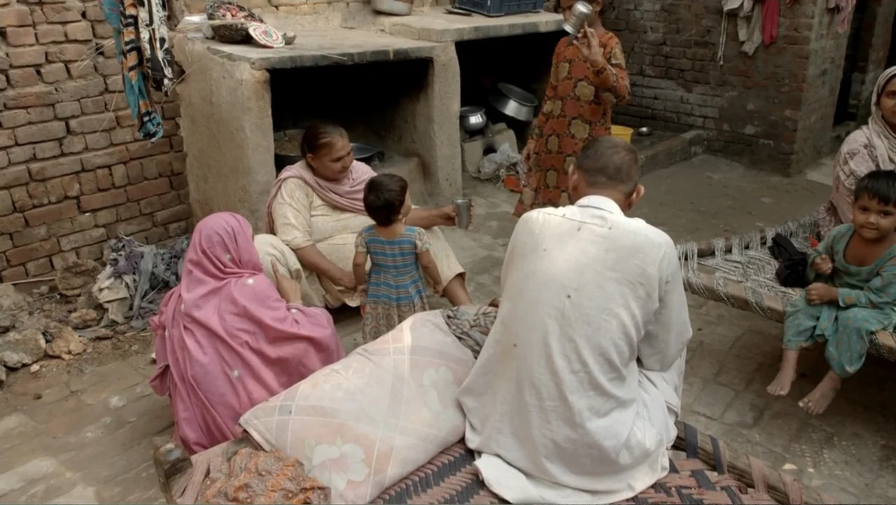 A Girl in the River: The Price of Forgiveness (2015) movie still: medium — A rural courtyard features brick walls and traditional woven cots.…