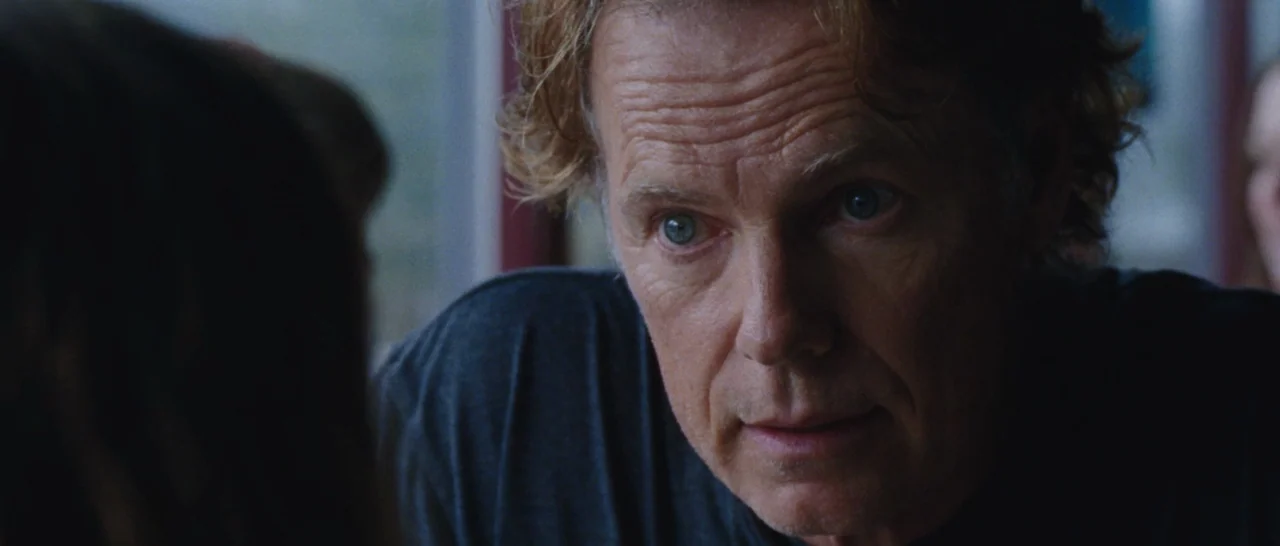 Wildlike (2014) movie still: closeup — An interior shot inside a booth with a man in a dark t-shirt. He looks toward an unseen person seated across…