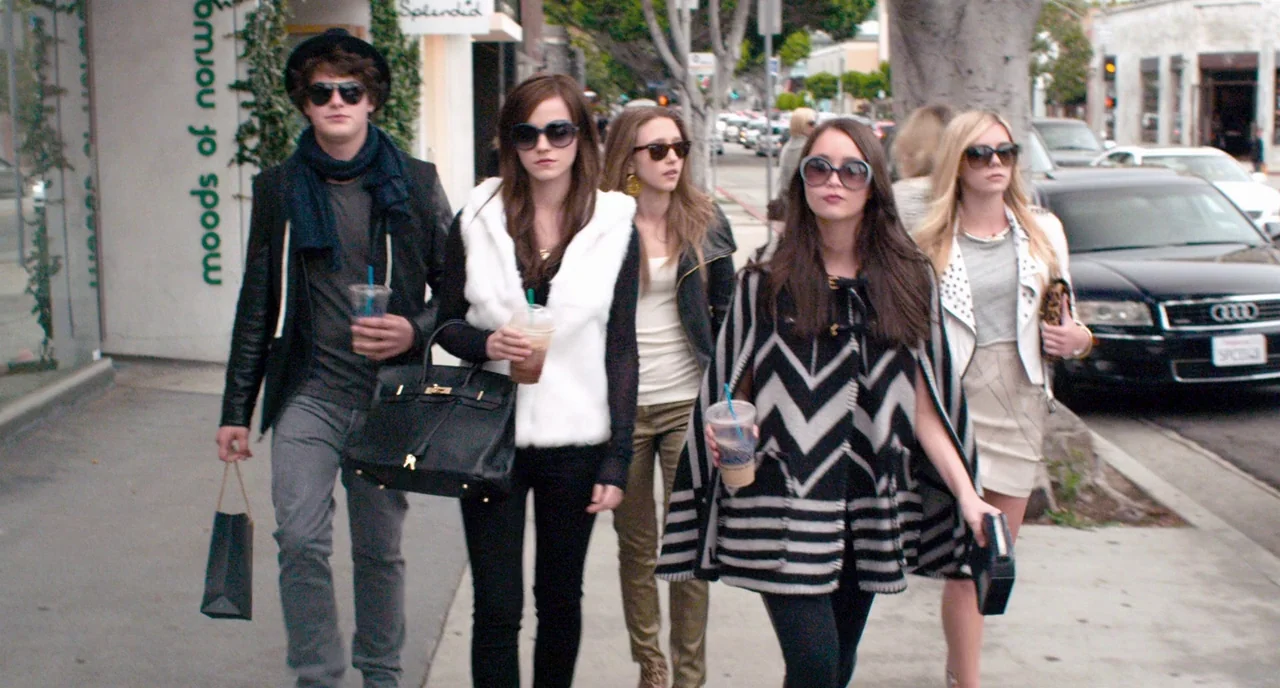 The Bling Ring (2013) movie still: fullbody — A group of five young adults walks in a line on a paved city sidewalk. They wear modern casual…
