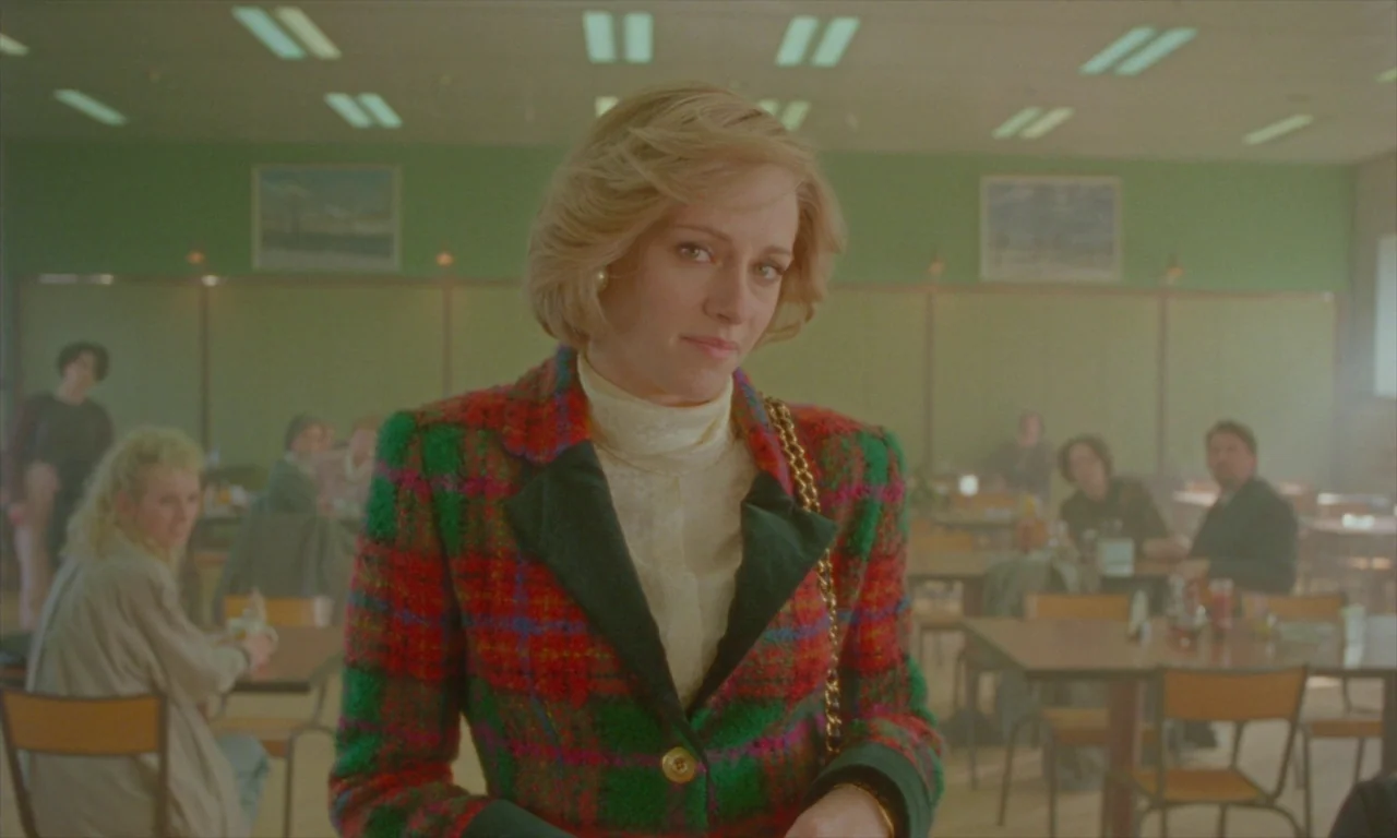 Spencer (2021) movie still: medium — A 1990s diner with green walls features several patrons seated at wooden tables. A woman with blonde hair…