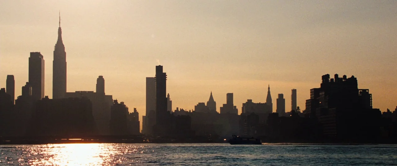 The Secret Life of Walter Mitty (2013) movie still: establishing — A dark, silhouetted skyline rises above a shimmering body of water at dusk. The…
