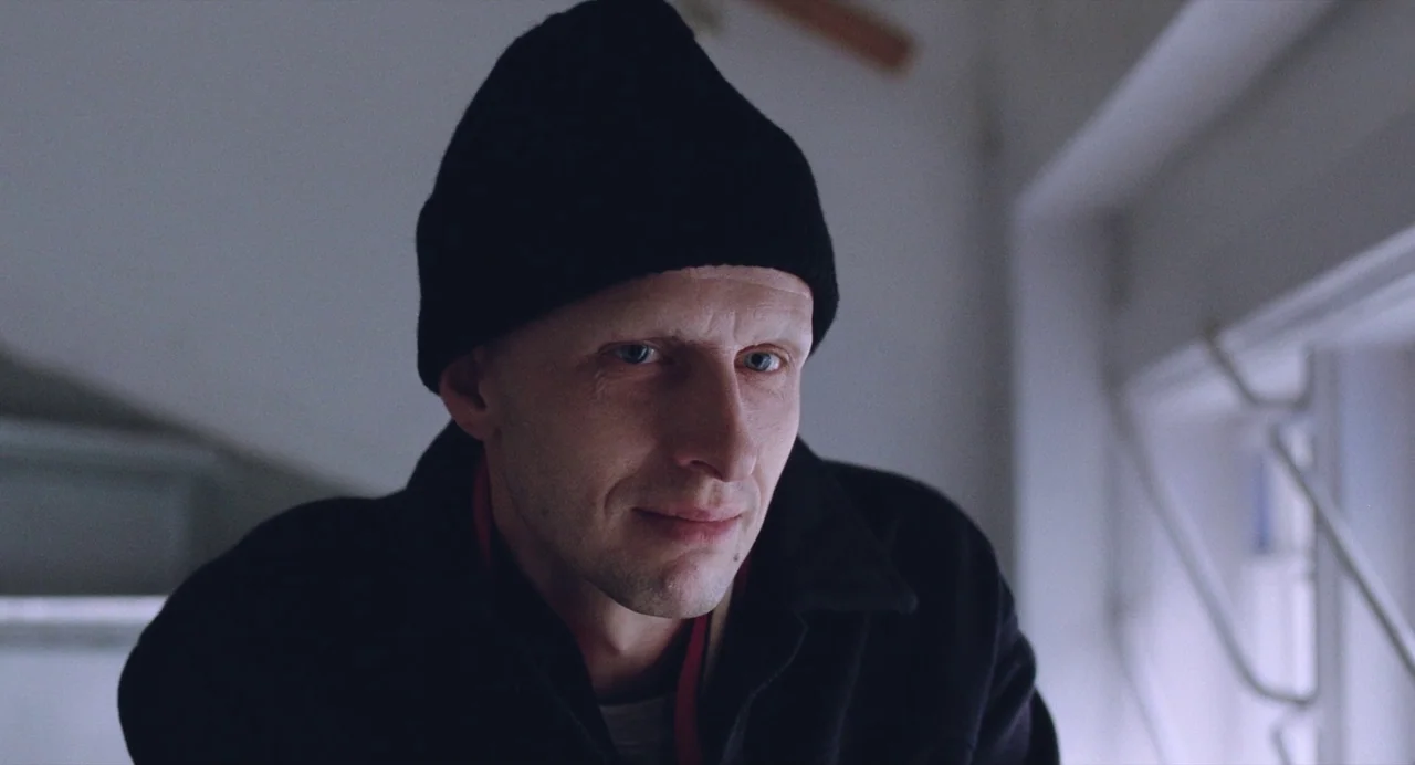 The Worst Person in the World (2021) movie still: closeup — An interior space with a window frame visible in the background out of focus. A man…