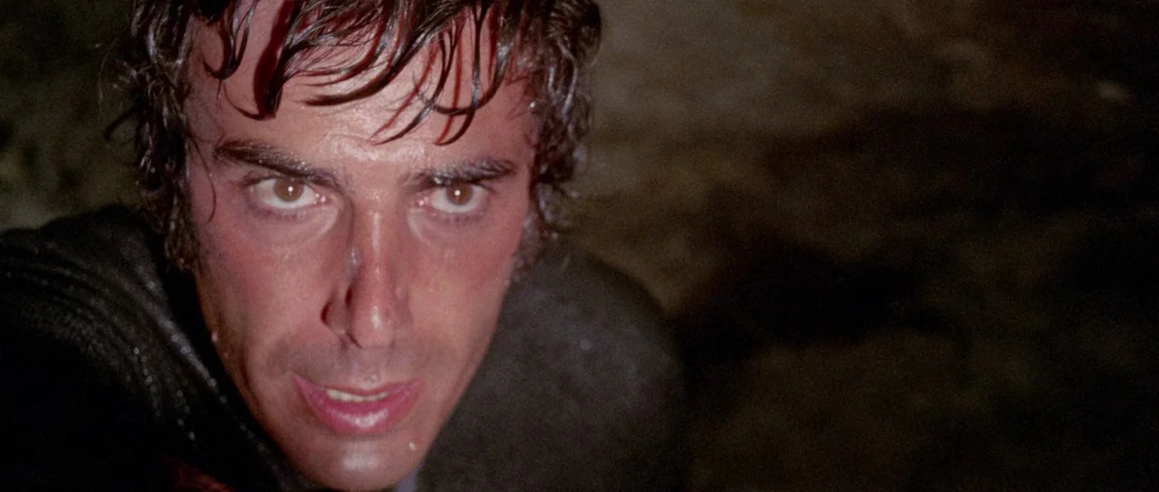 The Case of the Scorpion’s Tail (1971) movie still: closeup — A dark, rocky exterior environment with minimal ambient light. A wet-haired man stares…