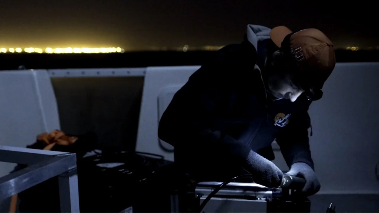 Air Jaws: Night Stalker (2016) movie still: medium — A dark, exterior boat deck at night features a lone person working. The subject wears gloves…
